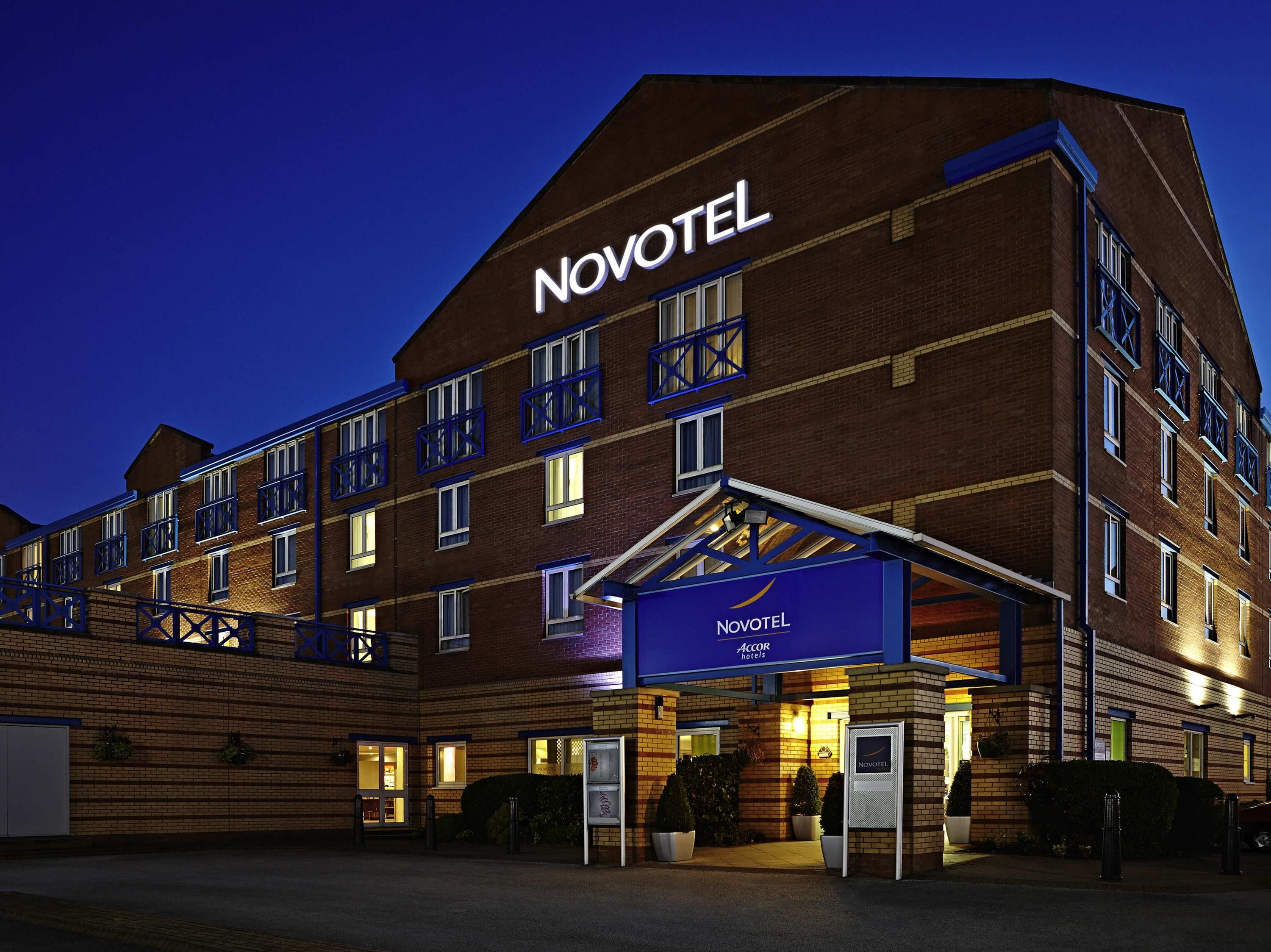 A Novotel hotel with a brick facade, multiple balconies, and a well-lit entrance.
