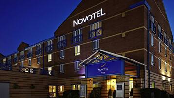 A Novotel hotel with a brick facade, multiple balconies, and a well-lit entrance.