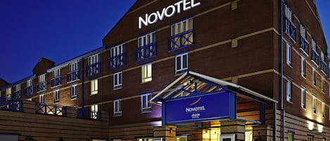 A Novotel hotel with a brick facade, multiple balconies, and a well-lit entrance.