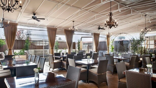 Un espace extérieur aménagé pour les repas, avec des tables et des chaises, des ventilateurs de plafond et des lampes suspendues.
