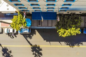 An aerial view of a parking lot with cars, trees, and a building with blue and white exterior.