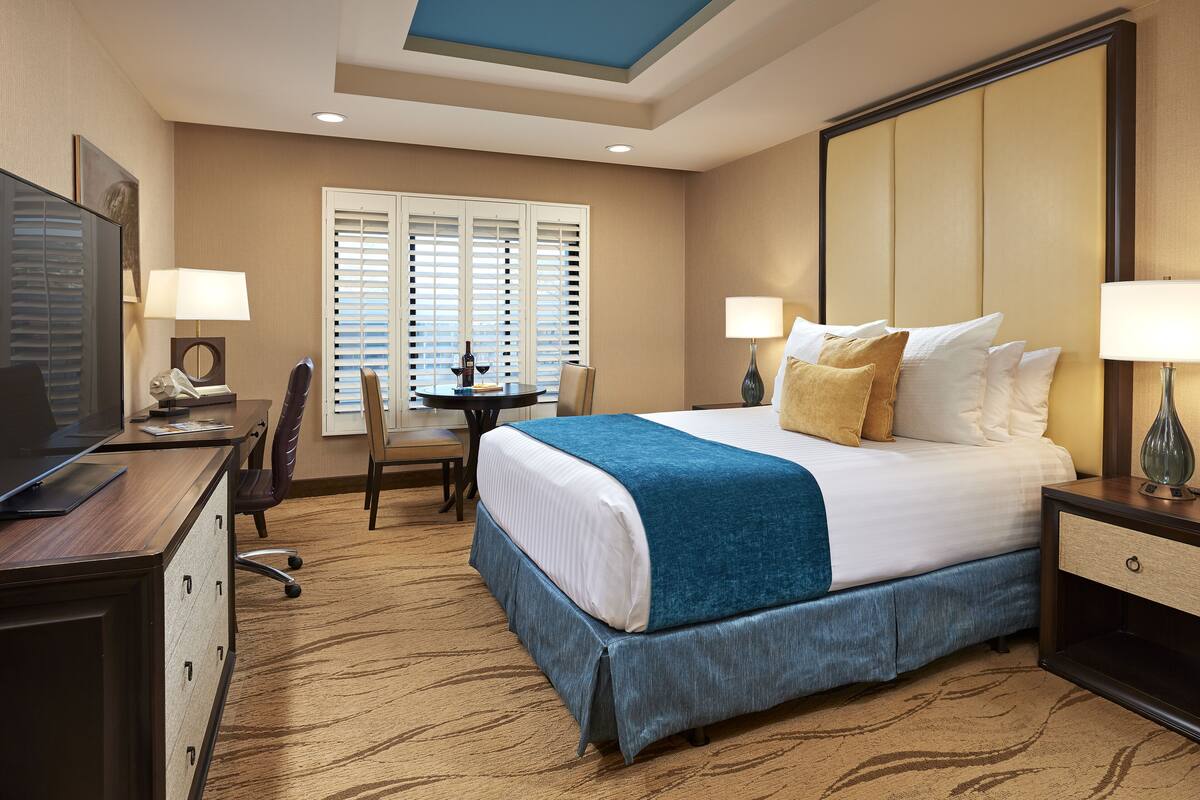 Une chambre d’hôtel avec un grand lit, un bureau avec un ordinateur, une chaise et un téléviseur.