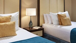 Une chambre d’hôtel avec deux lits, une table de chevet avec une lampe et un livre.