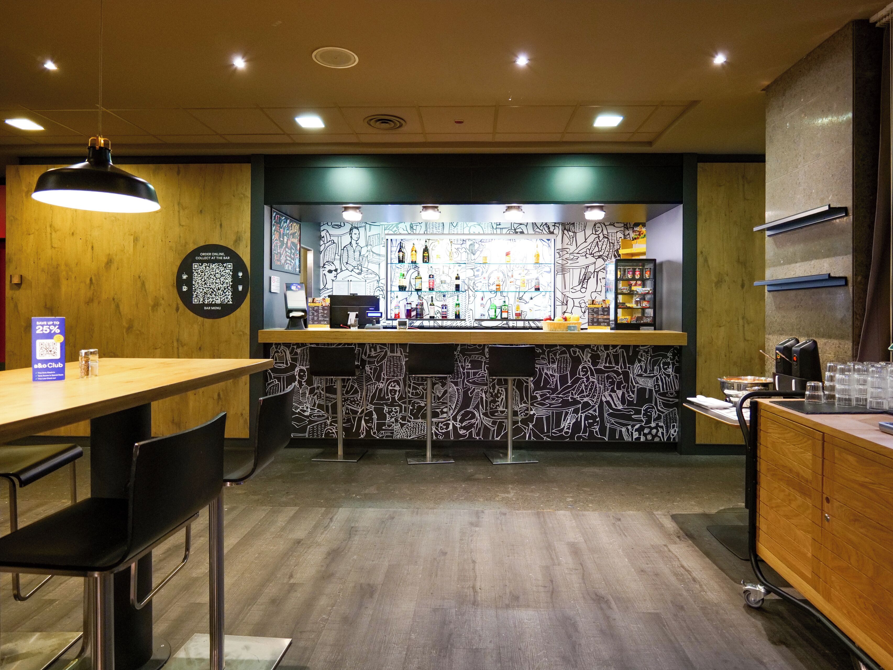 Eine Bar mit Theke, Barhocker, einem QR-Code-Schild und einer Speisekarte.