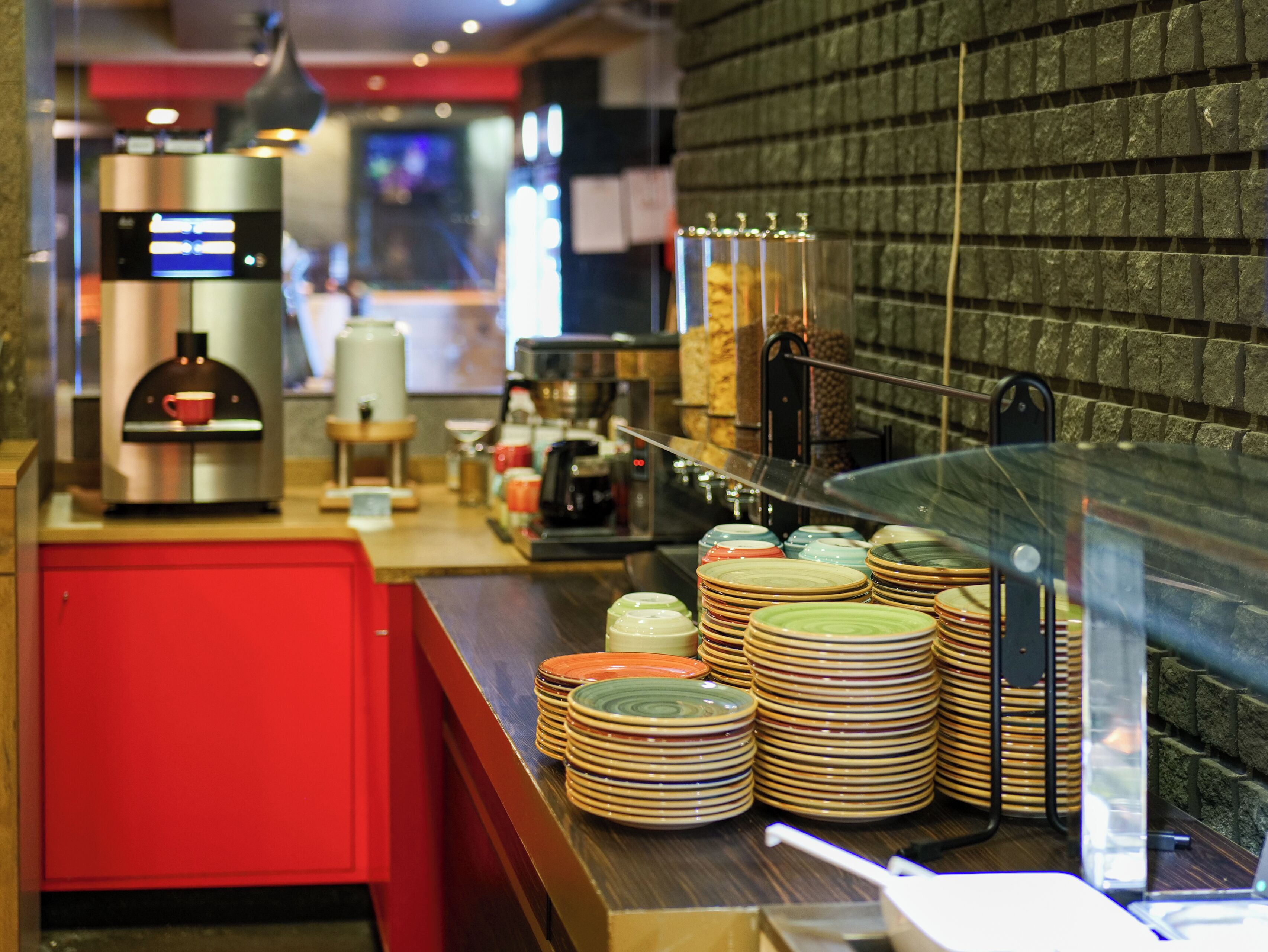 Interior de una cafetería con un mostrador que exhibe platos apilados y una máquina de café.