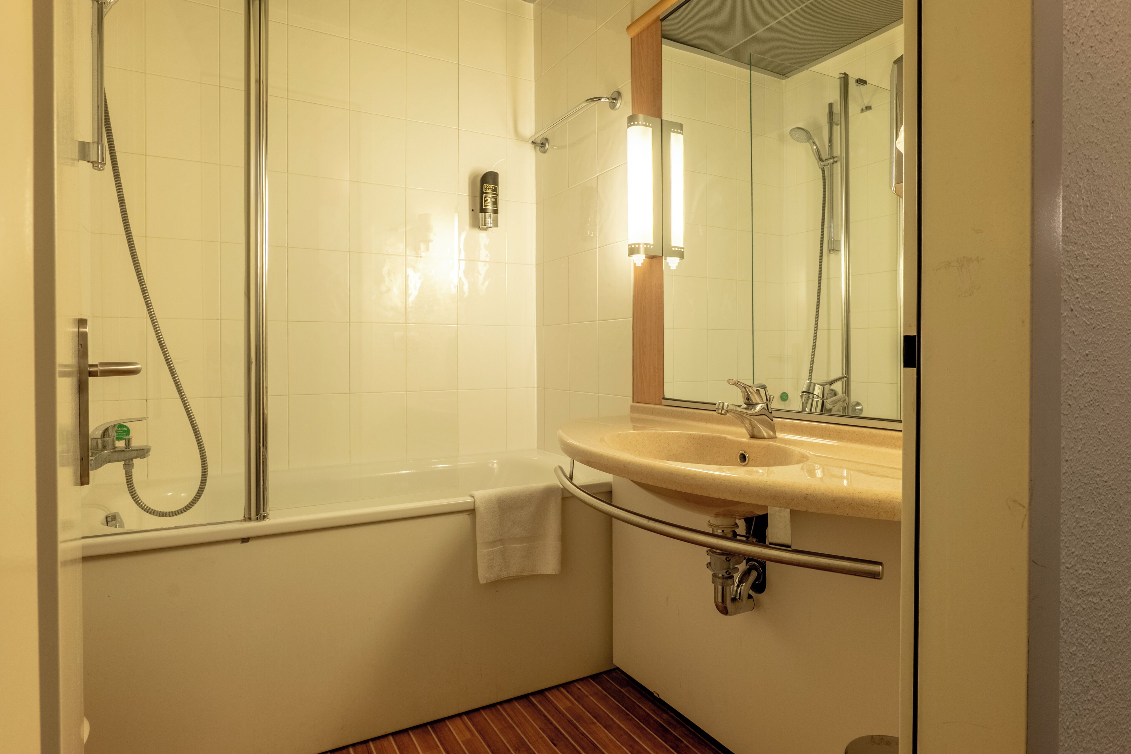 Un baño con bañera, lavamanos, espejo y ducha.