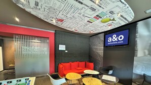 A modern lounge area with a foosball table, red sofa, and multiple seating options. - a&o Hostel Milano Ca Granda (Milan)