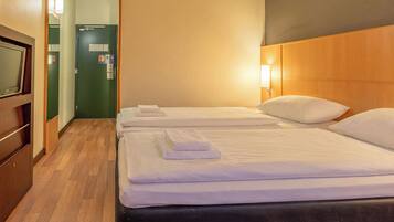 Une chambre d’hôtel avec deux lits, une télévision et une tête de lit en bois.