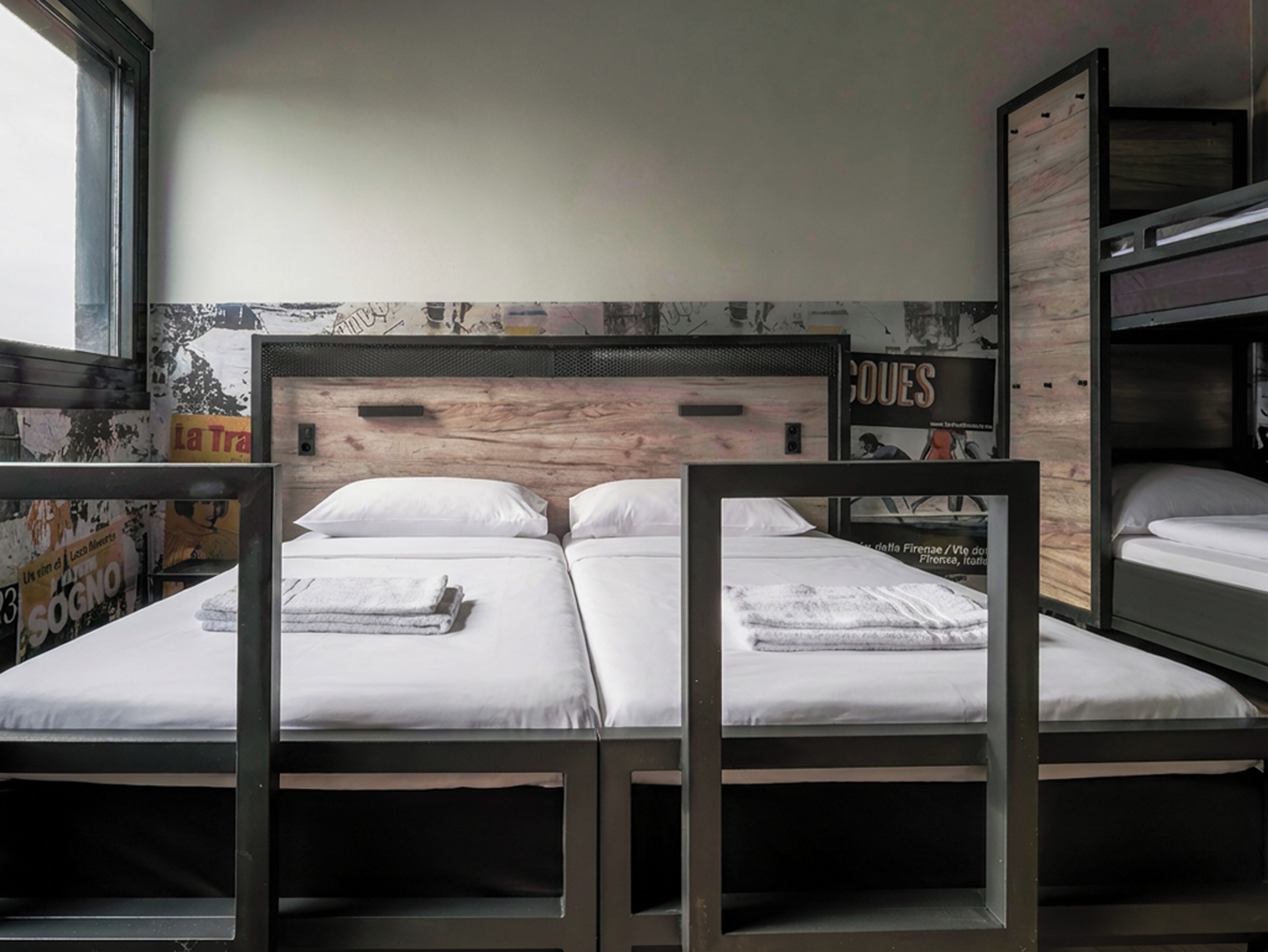 Una habitación tipo dormitorio con literas, un cabecero de madera y un cartel en la pared.