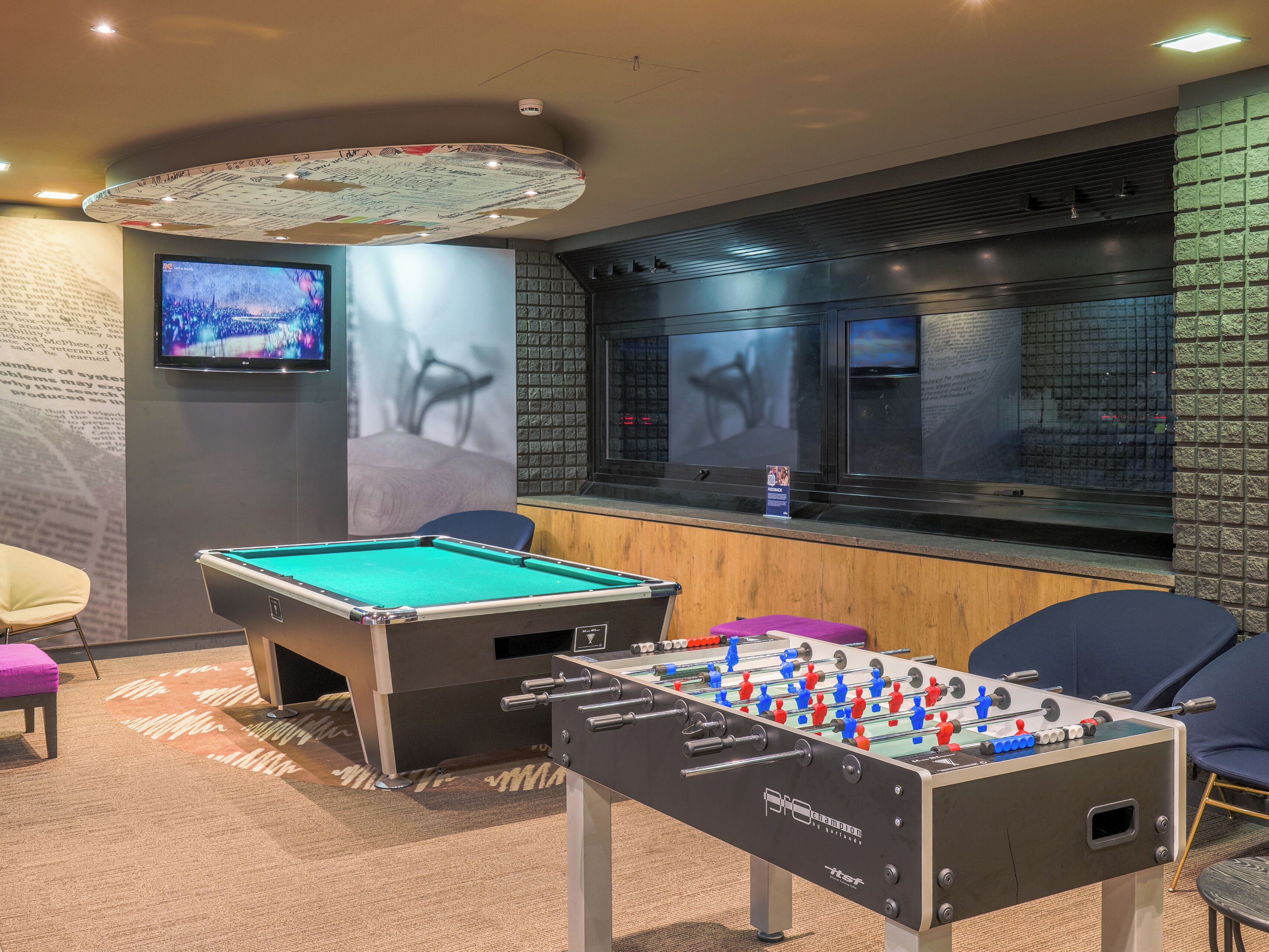 Una habitación con mesa de billar, mesa de fútbol de mesa y una zona de bar con televisor.