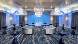 A spacious lobby with a large chandelier, round seating, and a blue accent wall. - Rosen Centre Hotel (Orlando)