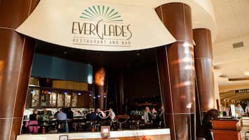 El interior del Restaurante y Bar EverClades, con una zona de bar, asientos y un mostrador de recepción.