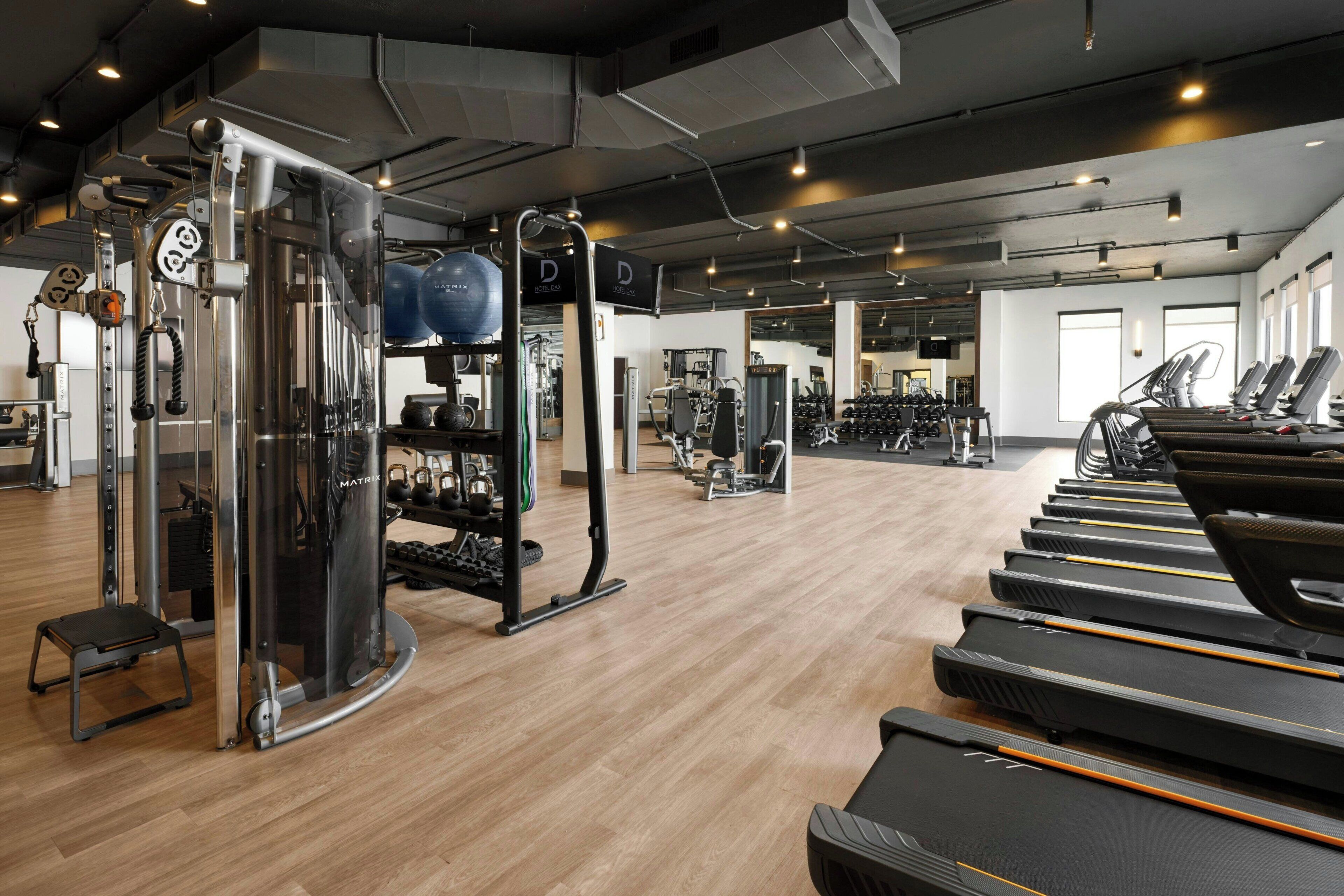 Une salle de sport équipée de tapis de course, d’appareils de musculation et d’un mur recouvert de miroirs.