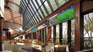 A spacious lobby with a high ceiling, large windows, and multiple seating areas. - Hotel Dax (Addison)