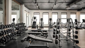 A gym with various exercise equipment, including dumbbells, benches, and weight machines.