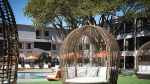 A poolside area with wicker cabanas, lounge chairs, and a swimming pool.
