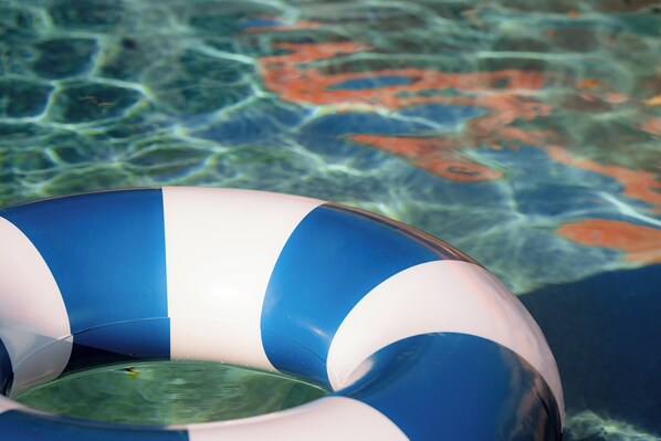 Vista clara de una piscina con un flotador inflable azul y blanco.