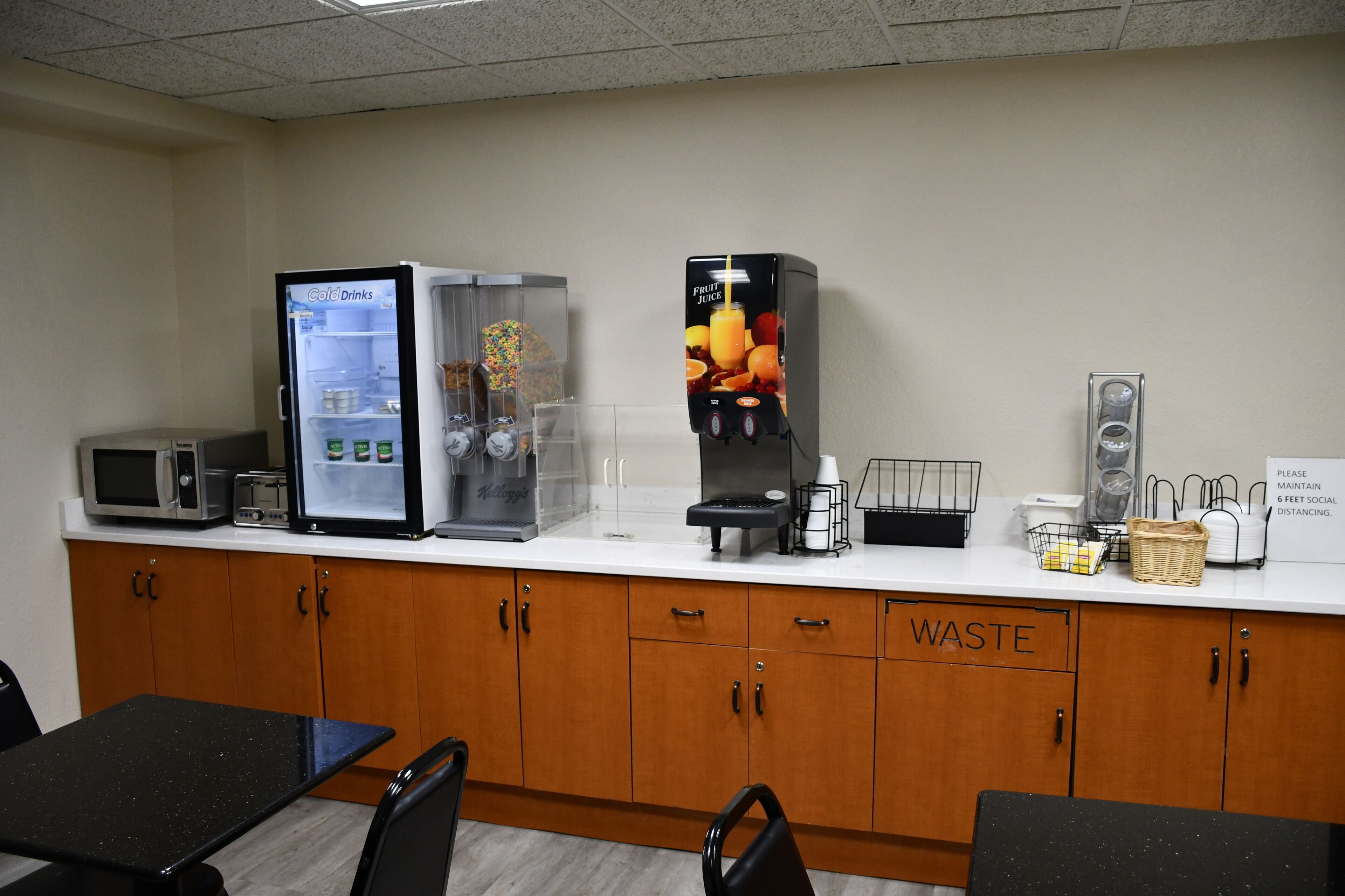 Una kitchenette equipada con microondas, refrigerador, cafetera y un cubo de basura.