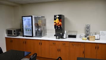 Una kitchenette equipada con microondas, refrigerador, cafetera y un cubo de basura.
