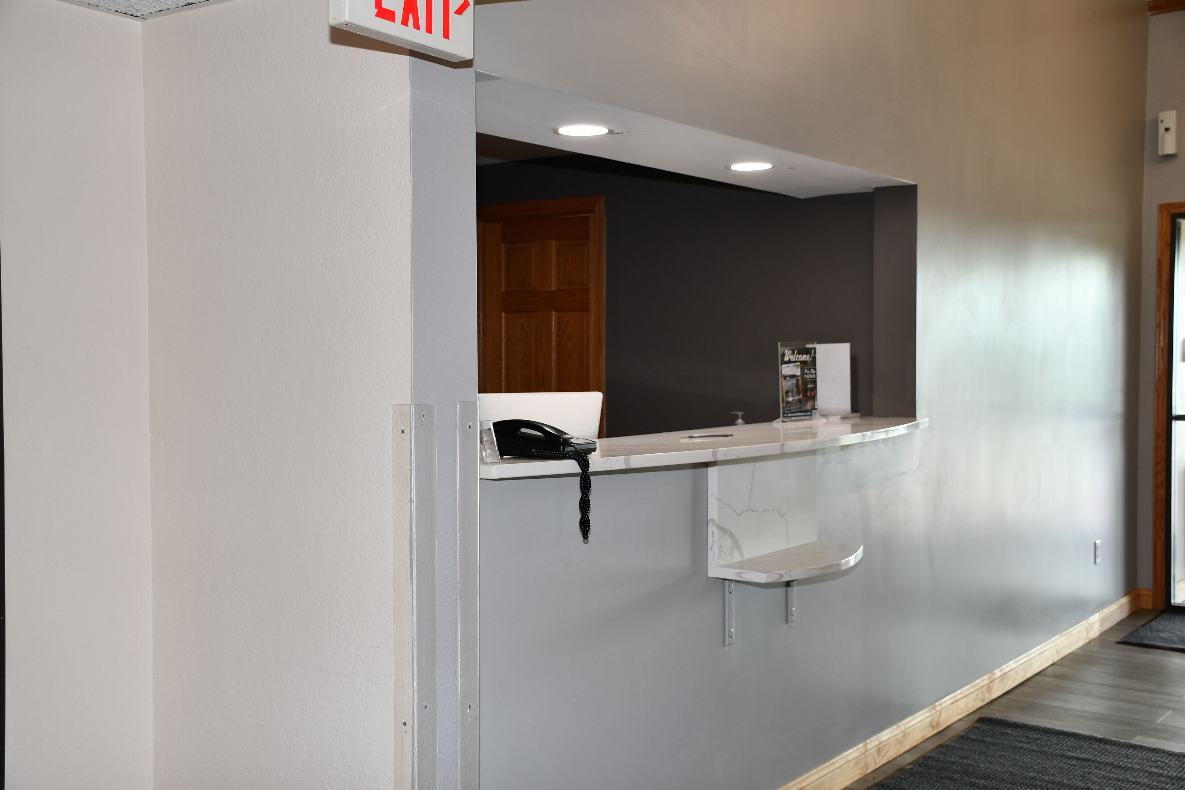 A reception desk with a phone, a small counter, and a sign that reads "EXIT".
