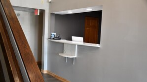 Un espace d’accueil comprenant un bureau, un ordinateur et une petite étagère.