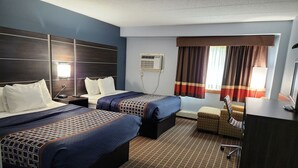 Une chambre d’hôtel avec deux lits, un bureau, une chaise, une télévision et une fenêtre avec des rideaux.
