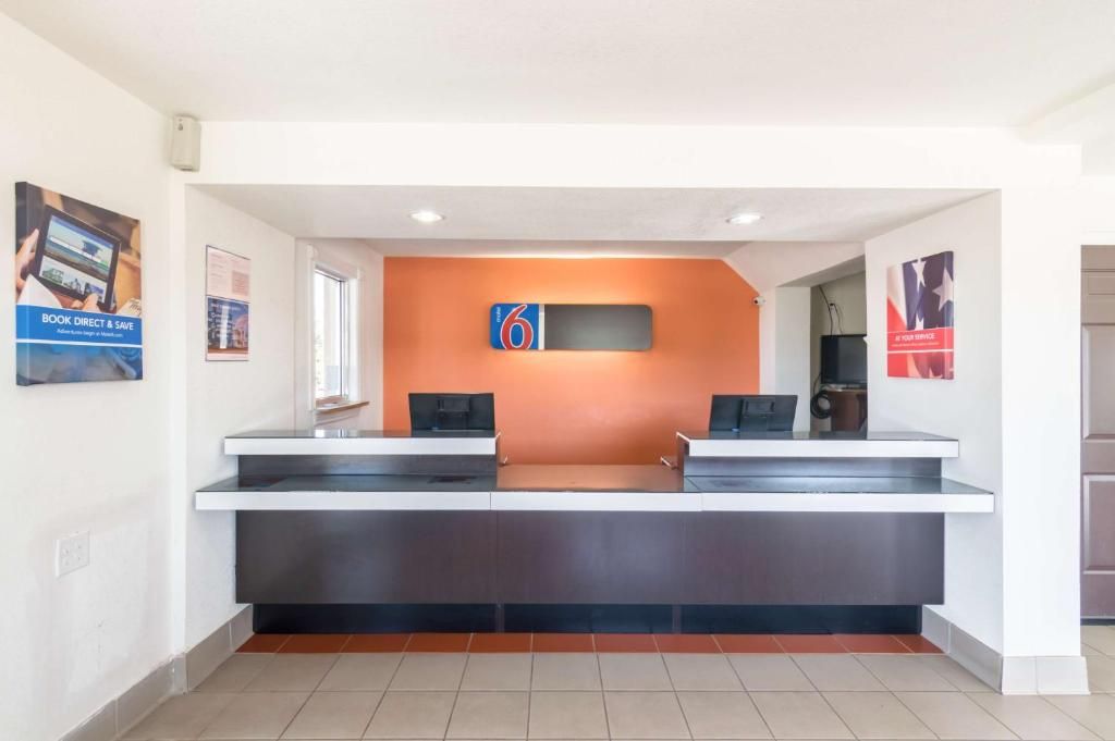 A reception desk with two counters, a digital clock, and a wall-mounted sign.