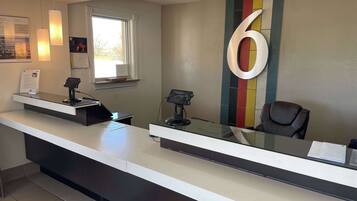 A reception desk with a large number '6' on the wall, a window, and a chair.