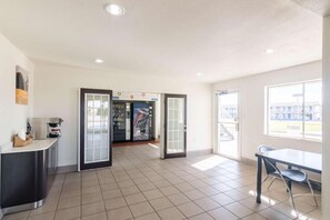 A hotel lobby with a reception desk, a vending machine, and a seating area with a table and chairs. - Motel 6 Wichita Falls, TX - North (Wichita Falls)