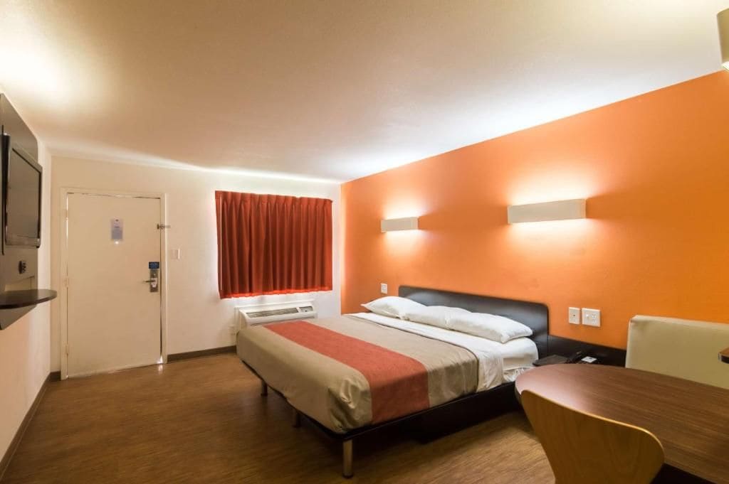 Una habitación de hotel con una cama, un escritorio y una ventana con cortinas.