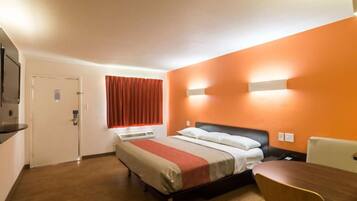 A hotel room with a bed, a desk, and a window with curtains.