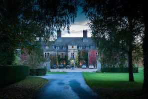 A large, historic building with a symmetrical facade, multiple chimneys, and a central entrance.