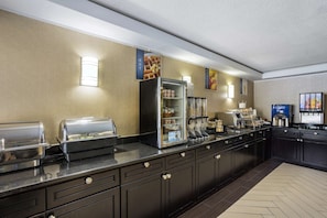 A buffet setup with various food stations, including a refrigerator, hot food display, and beverage dispensers.