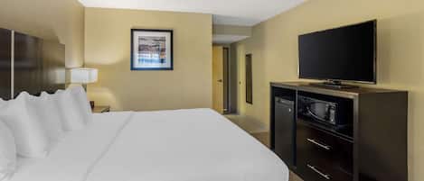 Habitación de hotel con una cama grande, televisión de pantalla plana, microondas y escritorio con cajones.
