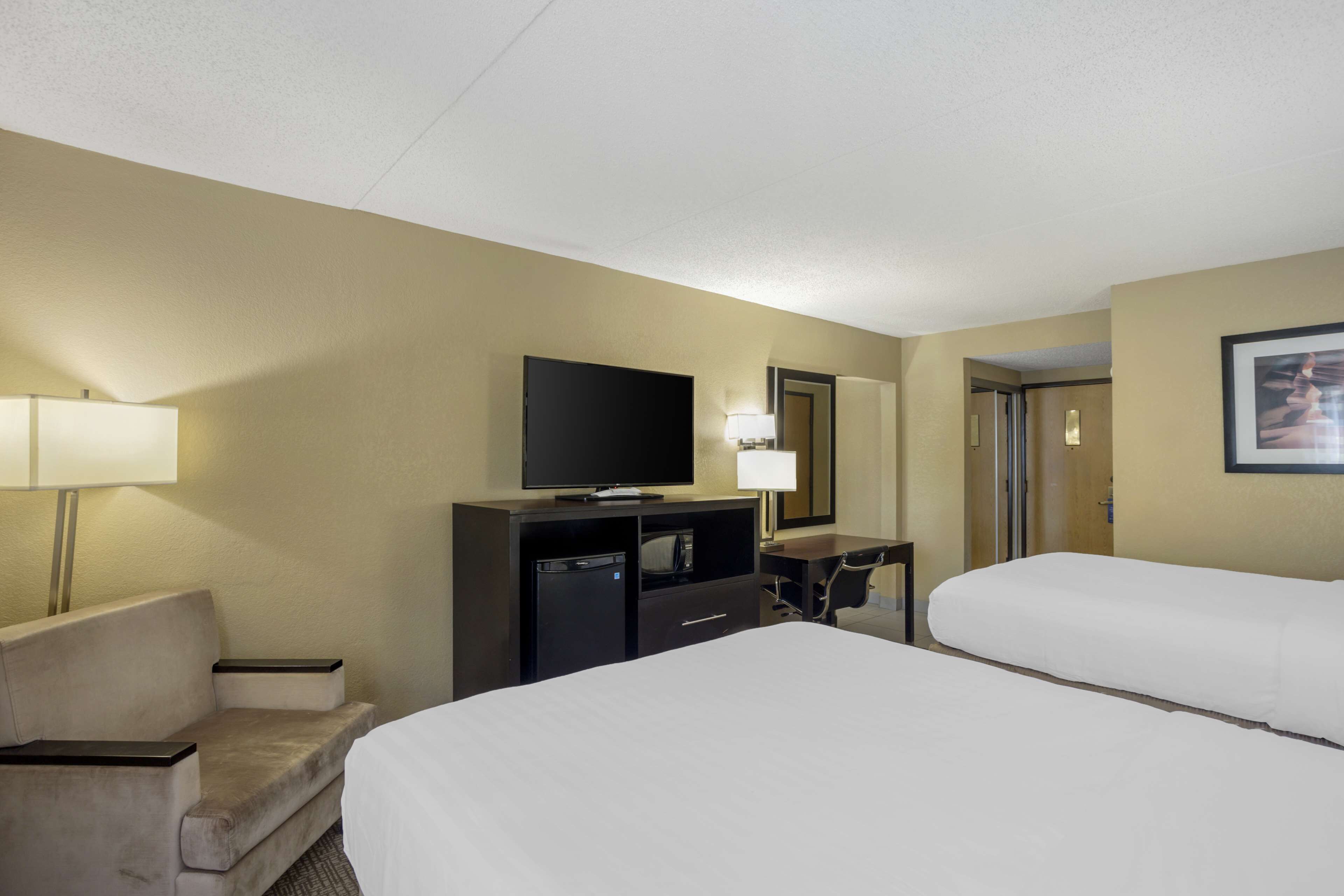 Une chambre d’hôtel avec deux lits, une télévision, un bureau et une chaise.