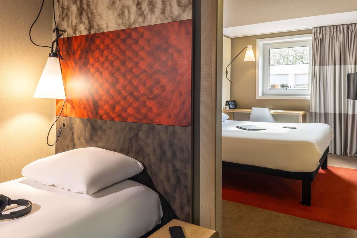 Ett hotellrum med en säng, ett nattduksbord, en lampa och utsikt över omgivningarna.