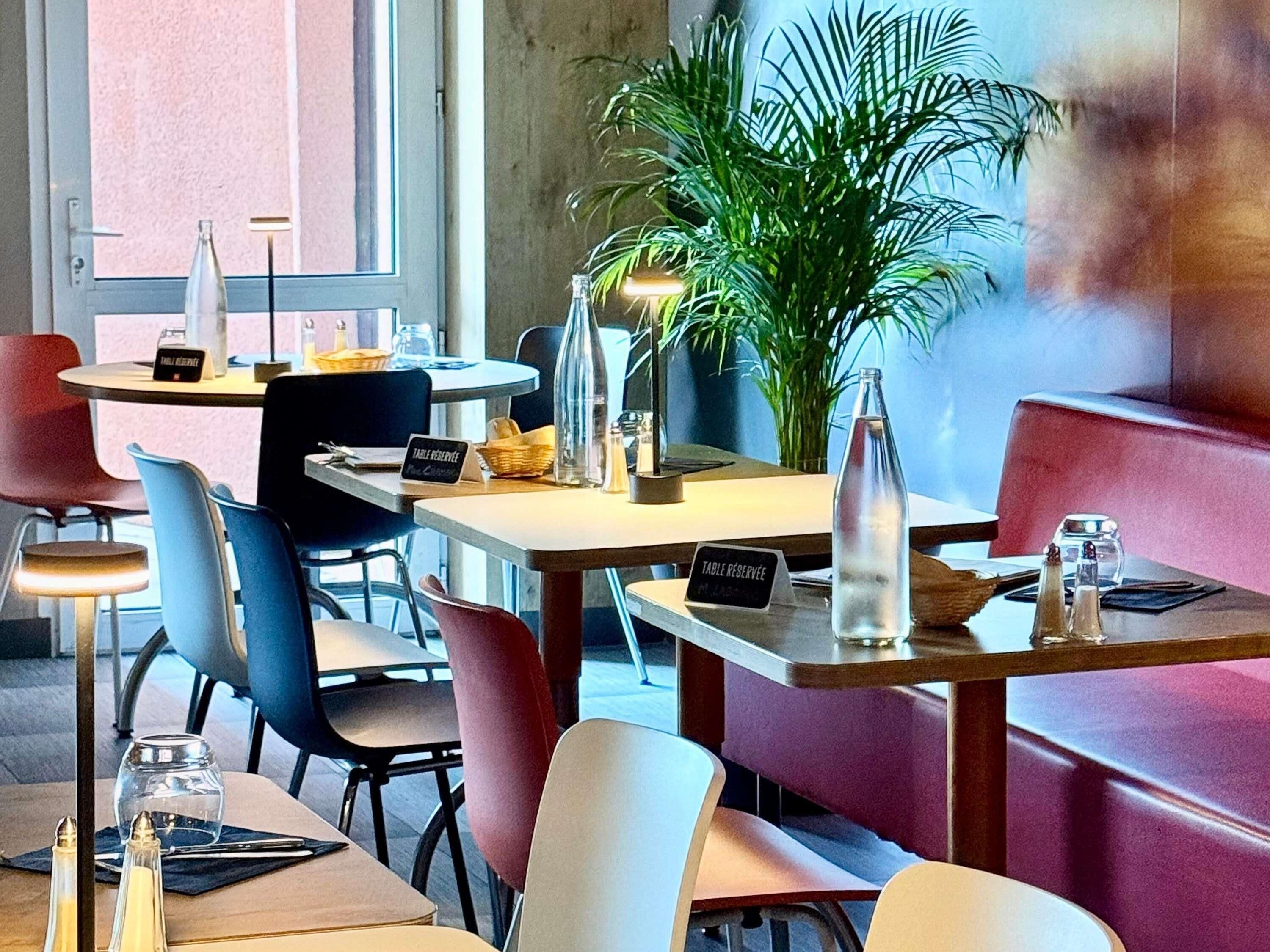 A restaurant with tables, chairs, a potted plant, and a sign indicating a table reservation.