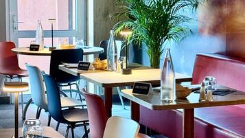 A restaurant with tables, chairs, a potted plant, and a sign indicating a table reservation.