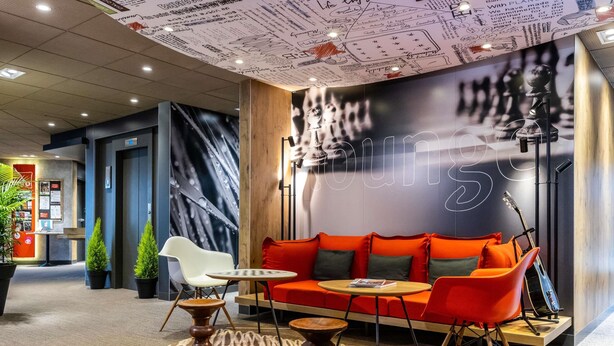 A modern lounge area with a red sofa, white chairs, and a small table. - ibis Toulouse Ponts Jumeaux (Toulouse)