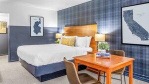 Ein Hotelzimmer mit einem großen Bett, einem hölzernen Kopfteil, einem Schreibtisch mit Stuhl und zwei Wandlampen.