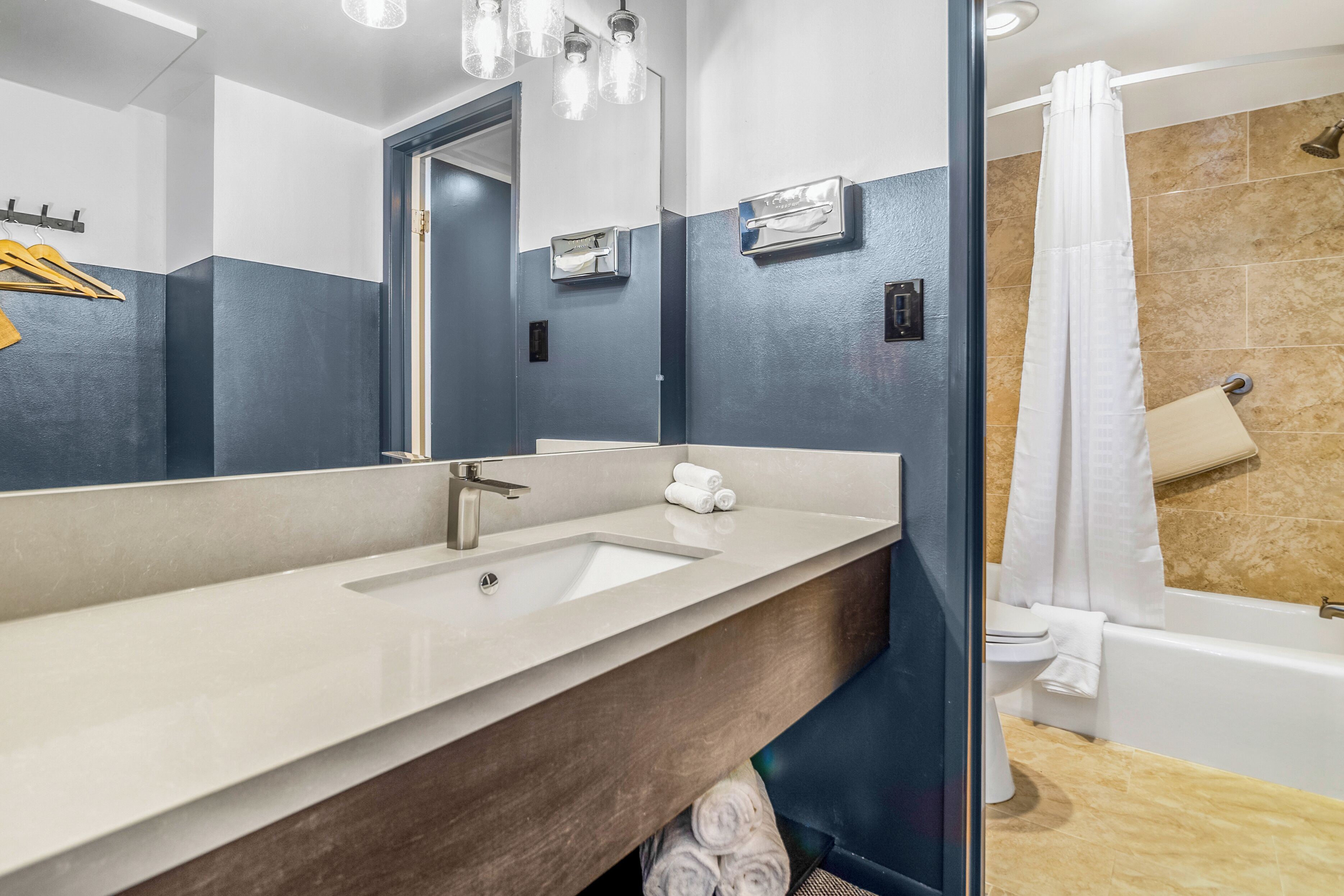 A modern bathroom with a large mirror, a sink, and a bathtub.