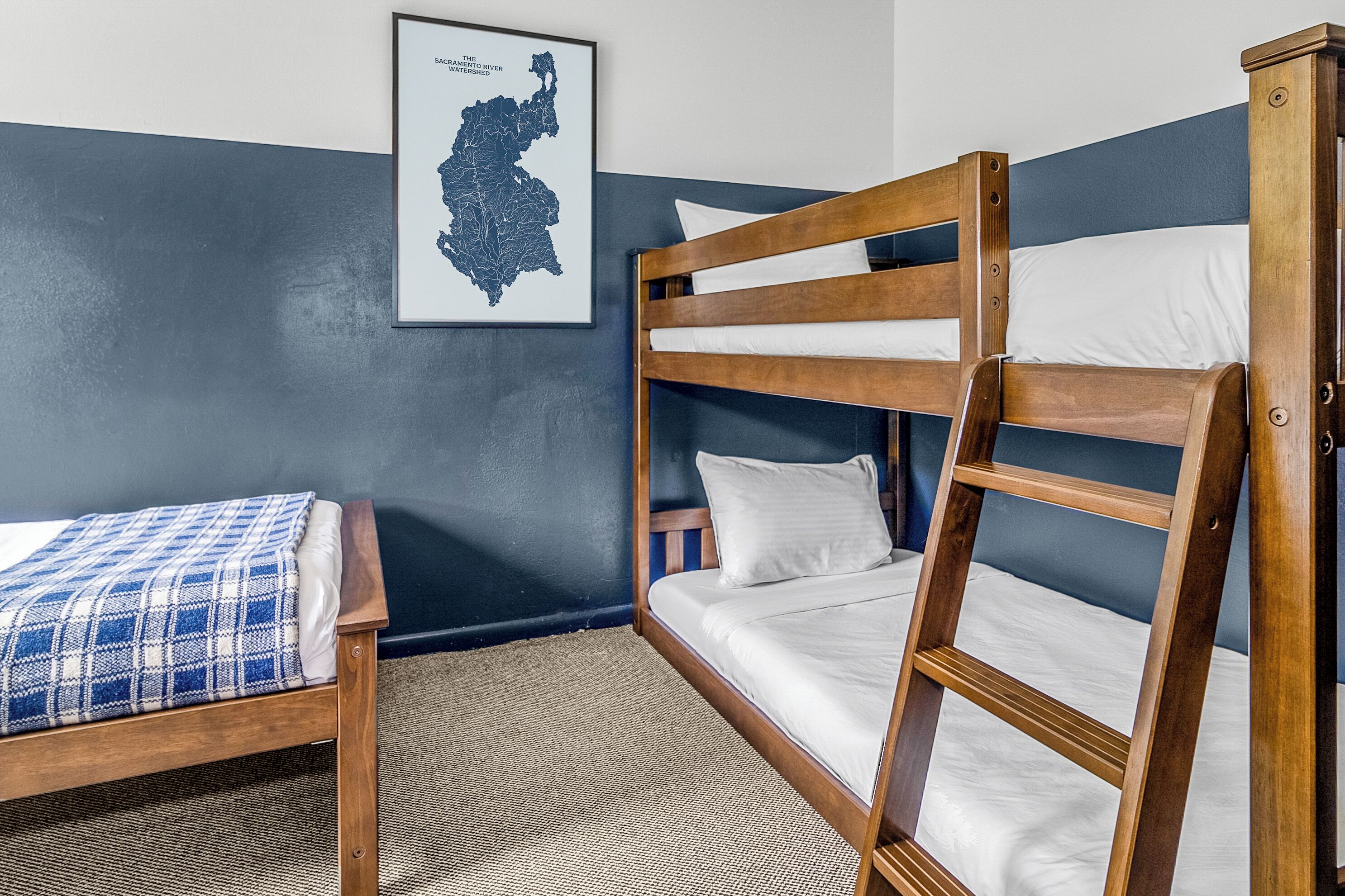 A bunk bed with white bedding and a blue and white checkered blanket on a lower bed.