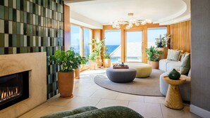 A modern living room with a fireplace, large windows, and a view of the sea. - Beach Terrace (Carlsbad)