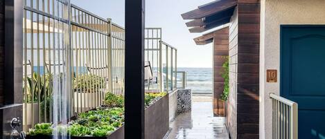 A narrow pathway leading to a balcony with a view of the sea.