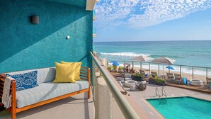 A balcony with a sofa, a pool, and a view of the ocean. - Beach Terrace (Carlsbad)