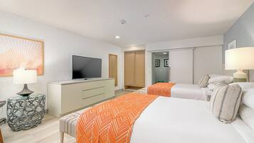A hotel room with two beds, a TV, a desk, and a lamp.