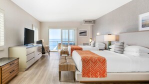 A hotel room with a large bed, a desk, a television, and a view of the ocean. - Beach Terrace (Carlsbad)