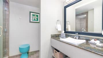 A modern bathroom with a turquoise toilet, a large mirror, and a granite countertop.