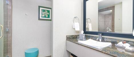 A modern bathroom with a turquoise toilet, a large mirror, and a granite countertop.