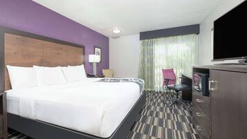 A hotel room with a large bed, a desk with a computer, a TV, and a chair.